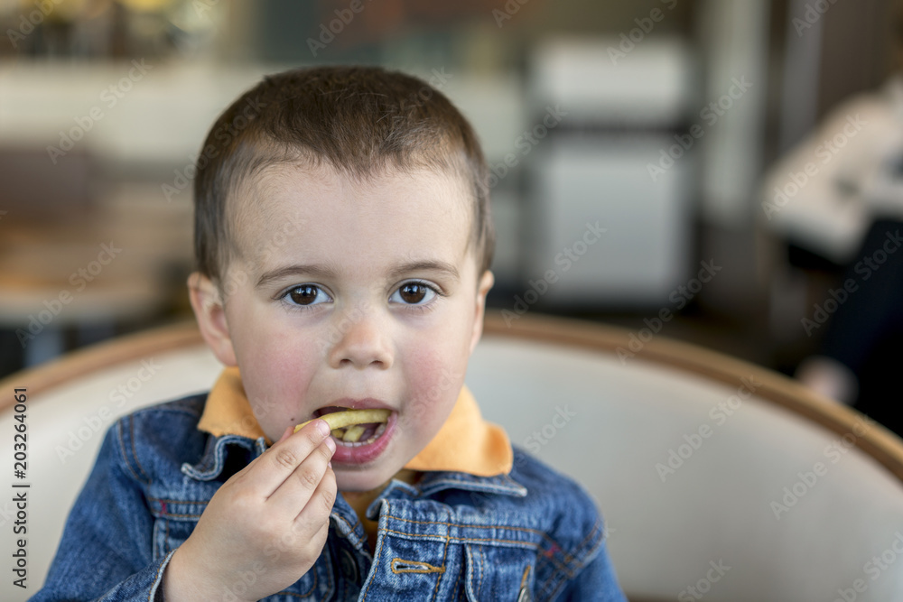 A happy baby boy eats French fries. fast food. European. boy 2 years old close-up eating french fries. A happy baby boy eats French fries. fast food. European. boy 2 years old close-up eating french fries.