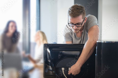 Computer technician attaching cable to computer in office