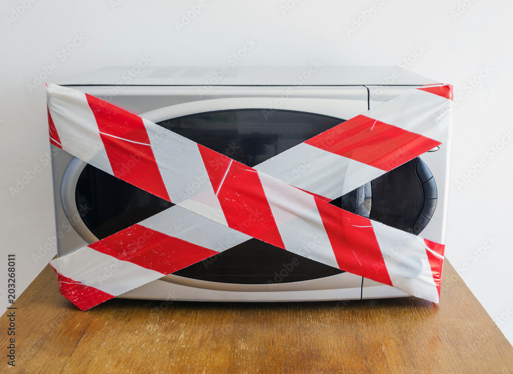 Closed electric microwave oven with red and white danger tape dieting