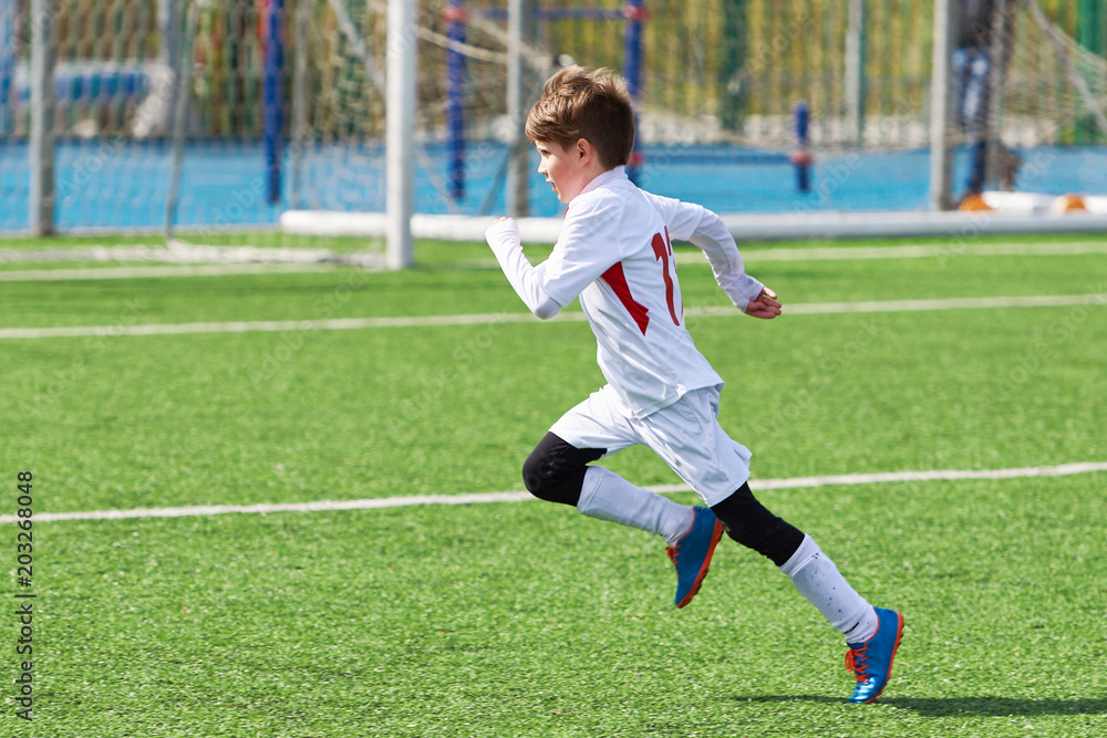 Running boy soccer player training on football field