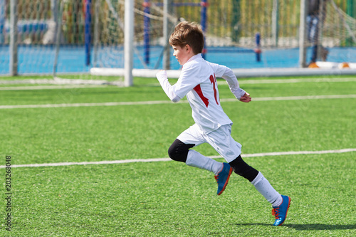 Running boy soccer player training on football field © Sergey Ryzhov