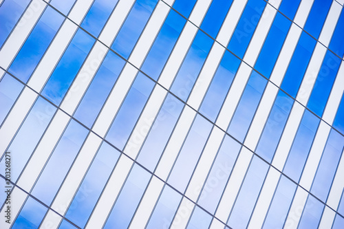 Angled metal lines frame windows reflecting blue sky and clouds.