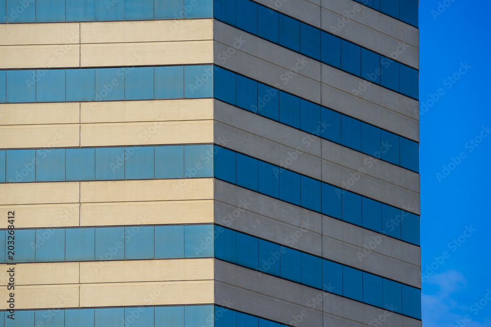 Angled lines of modern skyscraper stand beside an expanse of blue sky. Angled lines of modern skyscraper stand beside an expanse of blue sky.