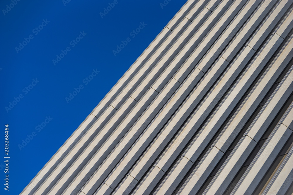 Parallel lines for the side of a highrise building under a deep blue sky.