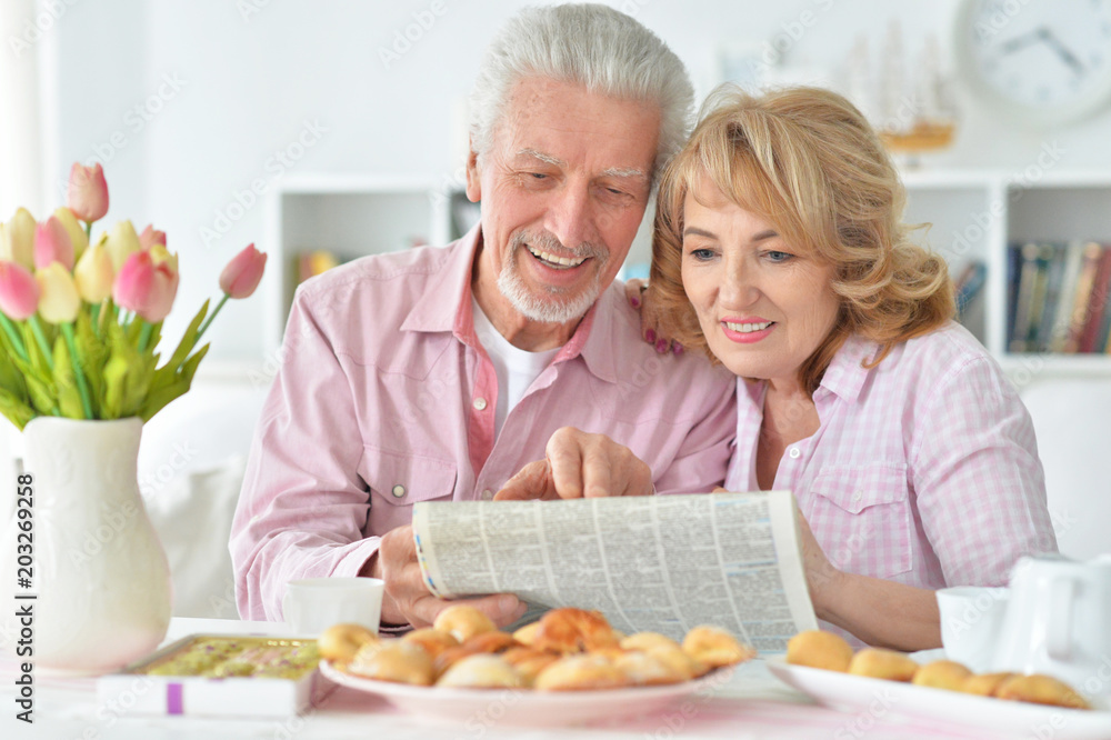 senior couple with newspaper at home senior couple with newspaper at home