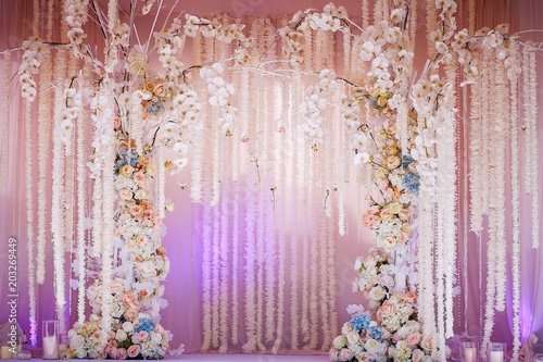 Wedding arch of fresh flowers. Delicate design of orchids and roses