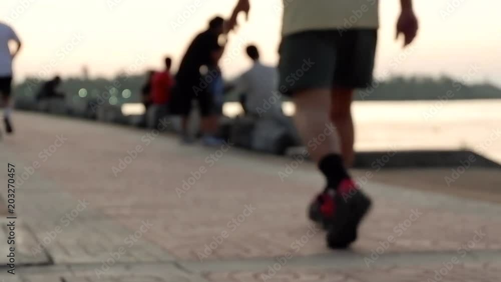 Blurred of people are running, walking and exercising in park with evening sunset and riverside background. Defocused of people outdoor activity background in spring and summer season. Blurred of people are running, walking and exercising in park with evening sunset and riverside background. Defocused of people outdoor activity background in spring and summer season.