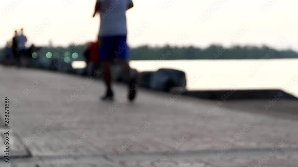 Blurred of people are running, walking and exercising in park with evening sunset and riverside background. Defocused of people outdoor activity background in spring and summer season. Blurred of people are running, walking and exercising in park with evening sunset and riverside background. Defocused of people outdoor activity background in spring and summer season.