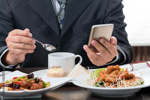 Close up of businessman checking the news from mobile phone while eatting breakfast on white background
