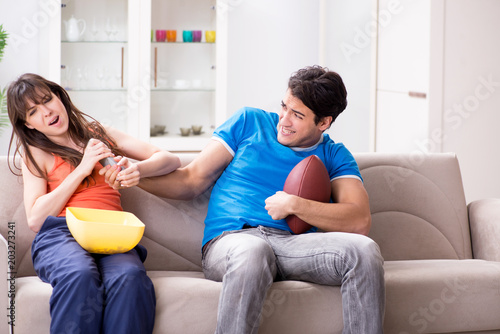 Man watching americal football with his wife