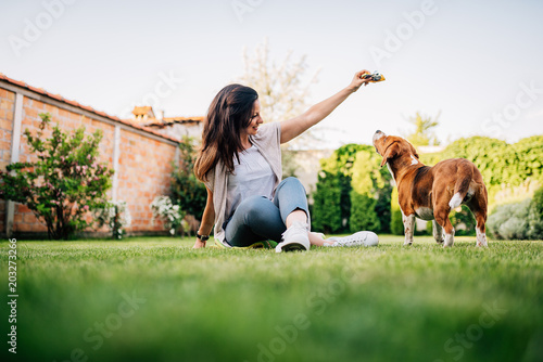 Photography Young woman giving a treat to her dog in the garden.