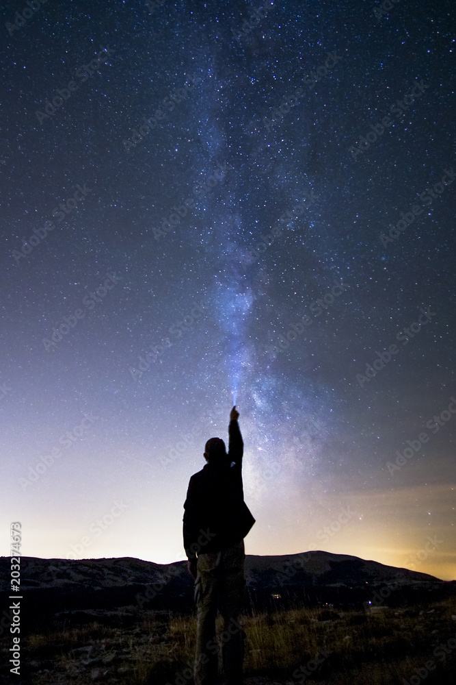 Un homme qui éclaire le ciel étoilé lors d’une belle nuit claire d’été