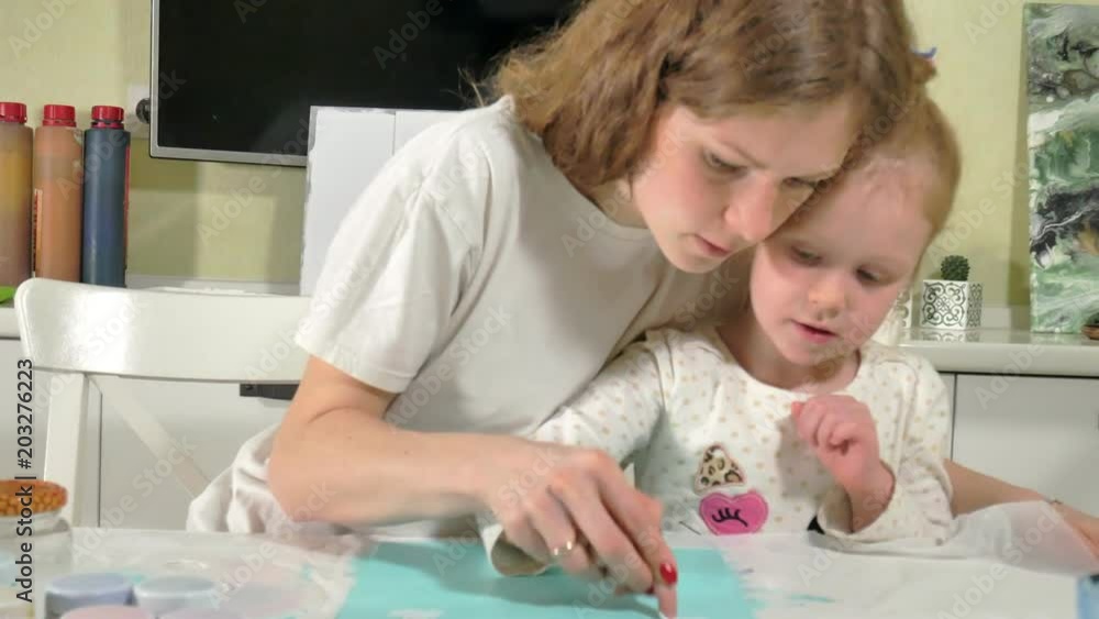 Mother and child paint with colored fingers. Games with children affect the development of early children. Mother and child paint with colored fingers. Games with children affect the development of early children.