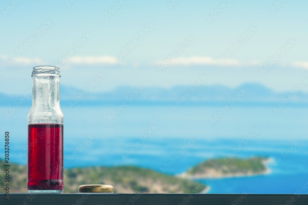 Pomegranate cold juice in bottles opposite on the islands and sea Pomegranate cold juice in bottles opposite on the islands and sea