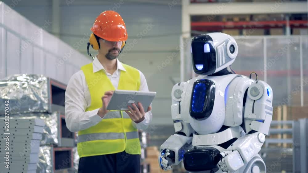 Factory employee is communicating with a humanoid in gestures Factory employee is communicating with a humanoid in gestures