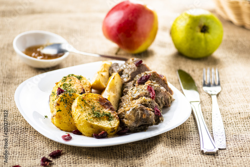 Duck fillet served with baked potatoes, apples and cranberries