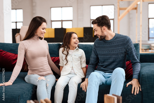 Young family with little girl sitting on sofa.