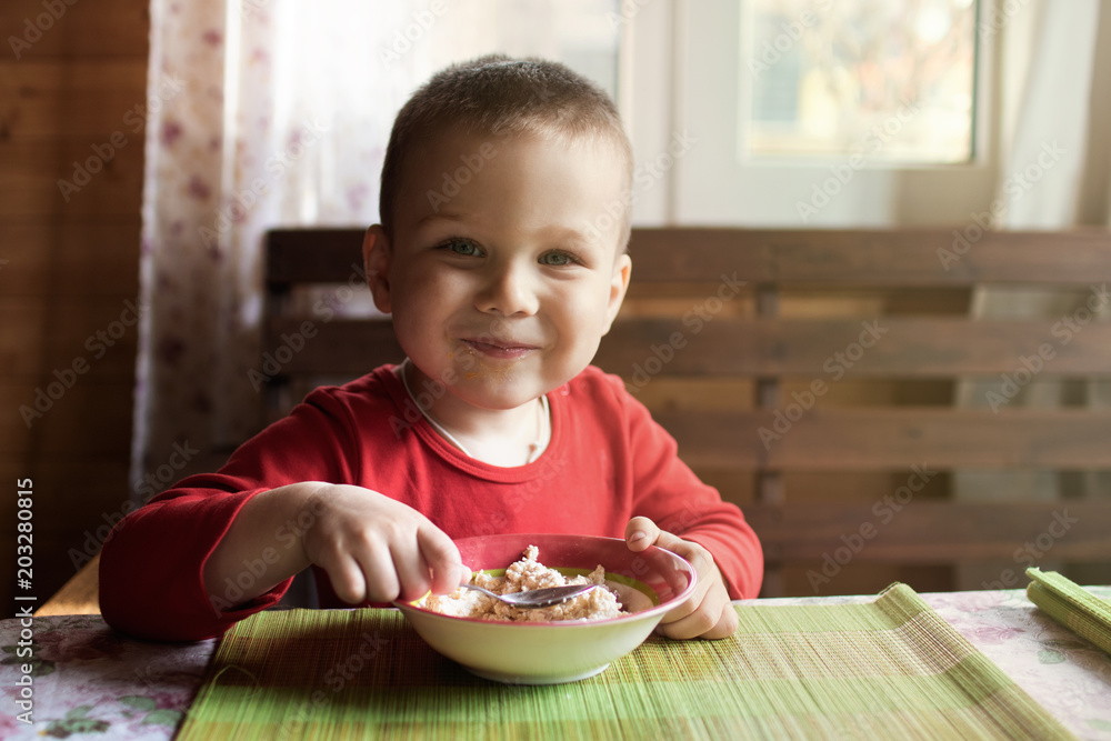 The little boy looks at the camera while eating breakfast. The little boy looks at the camera while eating breakfast.