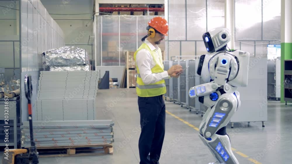 Factory cyborg is getting instructions from a male engineer Factory cyborg is getting instructions from a male engineer