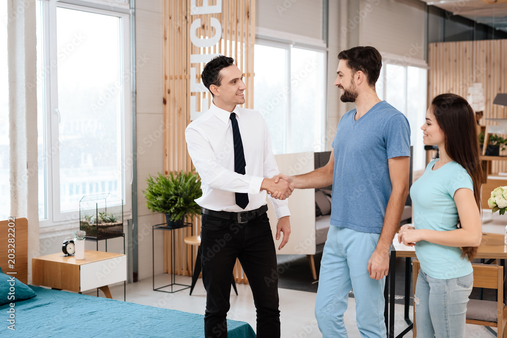 Two men shake hands in the furniture store. Two men shake hands in the furniture store.