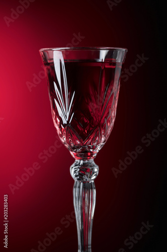 Close-up of crystal glass with red wine on dark background.