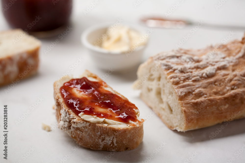 Homemade french bread baguette sliced with strawberry jam and butter Homemade french bread baguette sliced with strawberry jam and butter