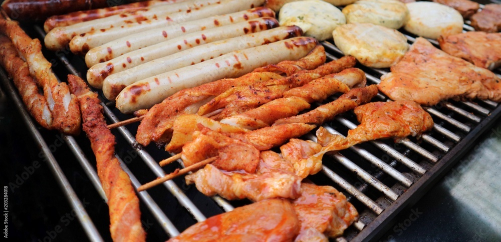 Various assorted meat on a grill. Grilling season concept. Sausages, meat rolls, grilled tofu. Delicious eating. Top view, close up