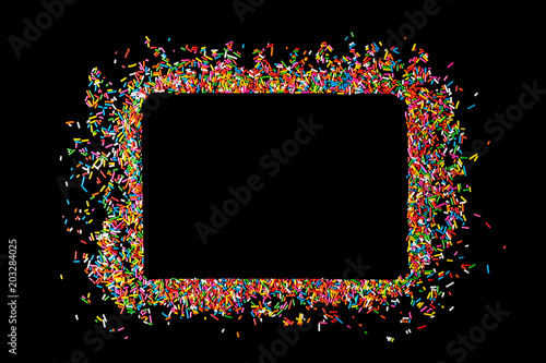 Border frame of colorful sprinkles on a black background with copy space. Top view or flat lay. Concept design for banner, poster and card
