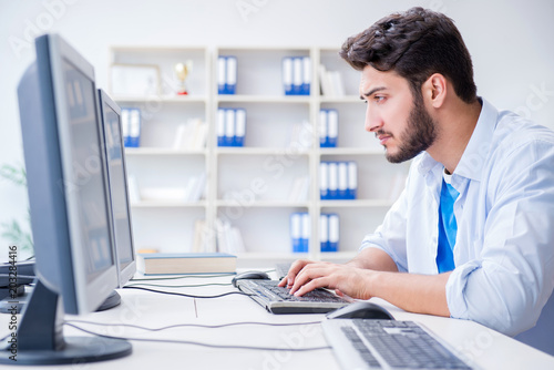 Businessman sitting in front of many screens