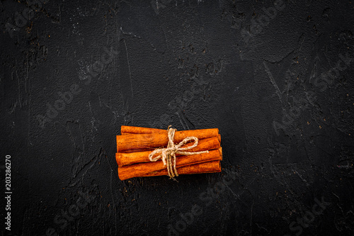 Bounded cinnamon sticks on black background top view copy space. Condiment for mulled wine