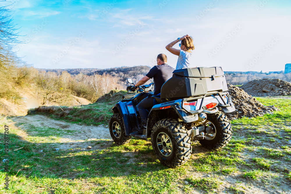 couple enjoys riding an ATV on forest hills couple enjoys riding an ATV on forest hills