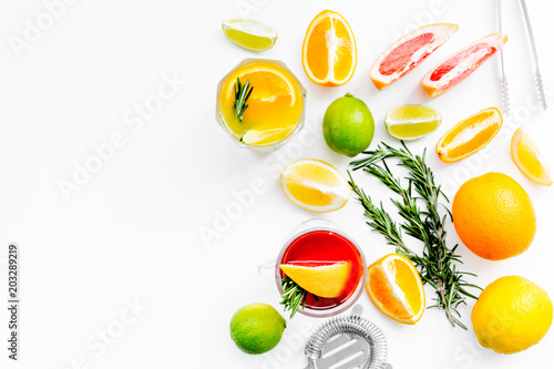 Bartender workplace for make fruit cocktail with alcohol. Strainer near citrus fruits and glass with cocktail on white background top view copy space