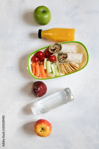 Healthy lunch box with sandwich and fresh vegetables, fruits, bottle of water and juice. from top view
