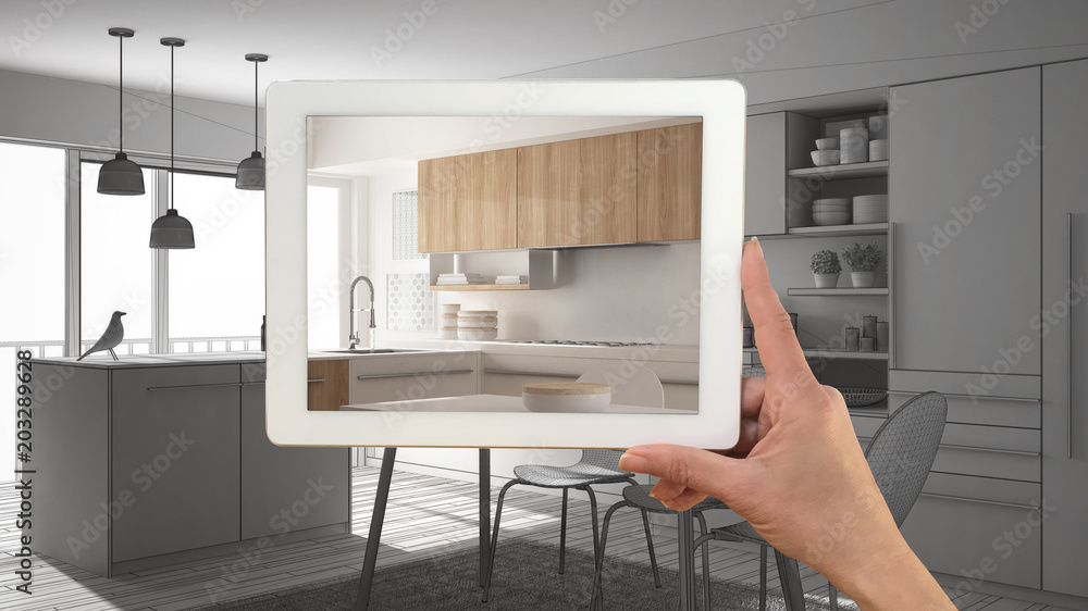 Hand holding tablet showing real finished minimalist white and wooden kitchen. Modern kitchen CAD sketch or drawing in the background, architecture interior design presentation Hand holding tablet showing real finished minimalist white and wooden kitchen. Modern kitchen CAD sketch or drawing in the background, architecture interior design presentation