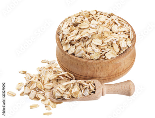 Isolated oat flakes. Wooden bowl and scoop with oatmeal on white background. Close-up
