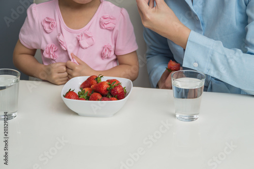 Parents and children are eating strawberries happily.