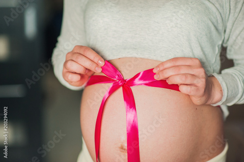Wallpaper Mural A pregnant woman touches her stomach. On his stomach a pink bow is tied. A woman expects that a girl will be born Torontodigital.ca