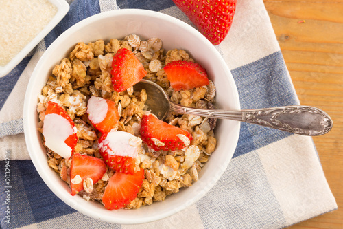 Bowl of cereals with strawberries resting on a blue napkin