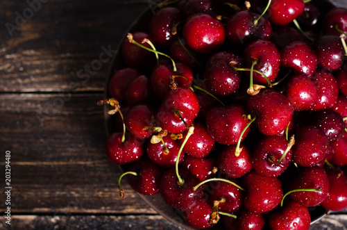 Cherries in a brown bowl on a wooden table. Free space for your text