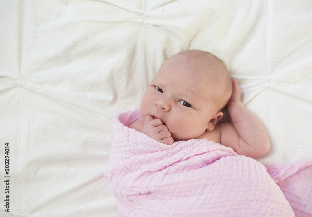 Overhead portrait of cute newborn baby girl lying on bed at home Overhead portrait of cute newborn baby girl lying on bed at home
