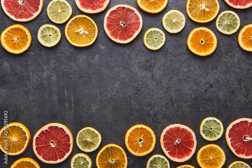 Flat lay of citrus fruits pattern of lemon  orange and grapefruit on black stone background. Copy space in the middle. Top view.