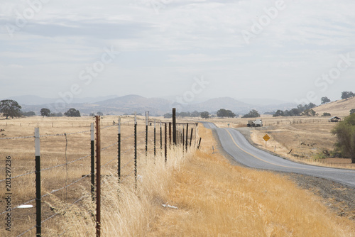 rolling hills and meadow with fence by road