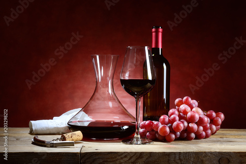 Red wine glass with bunch of grapes and decanter