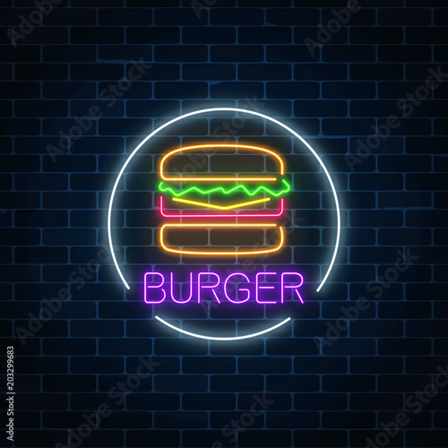 Neon glowing sign of burger in circle frame on a dark brick wall background. Fastfood light billboard symbol.