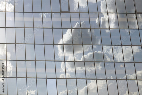 Horizontal shot of clouds reflected in the windows of a modern office building.