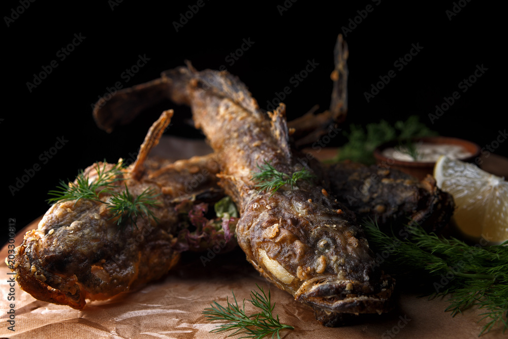 Fototapeta premium Fried fish goby with sauce on a wooden board