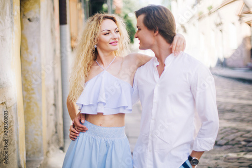 Happy newlywed couple on a relaxing walk in sunny Paris during summer honeymoon, smiling man hugging beautiful woman in hipster blue top and skirt outdoors