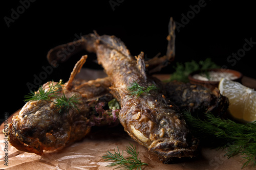 Fried fish goby with sauce on a wooden board