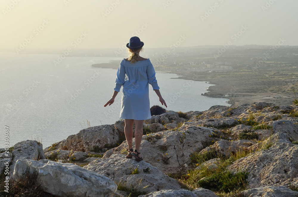 Woman traveler with enjoying view at mountains in Cape Greco, Cyprus, Mediterranean Sea. Traveling along mountains, freedom and active lifestyle concept