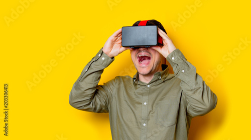 Young man using a VR glasses. Portrait on yellow background © Simonforstock